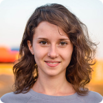 Mary Smiling young woman outdoors with soft lighting and a blurred background.